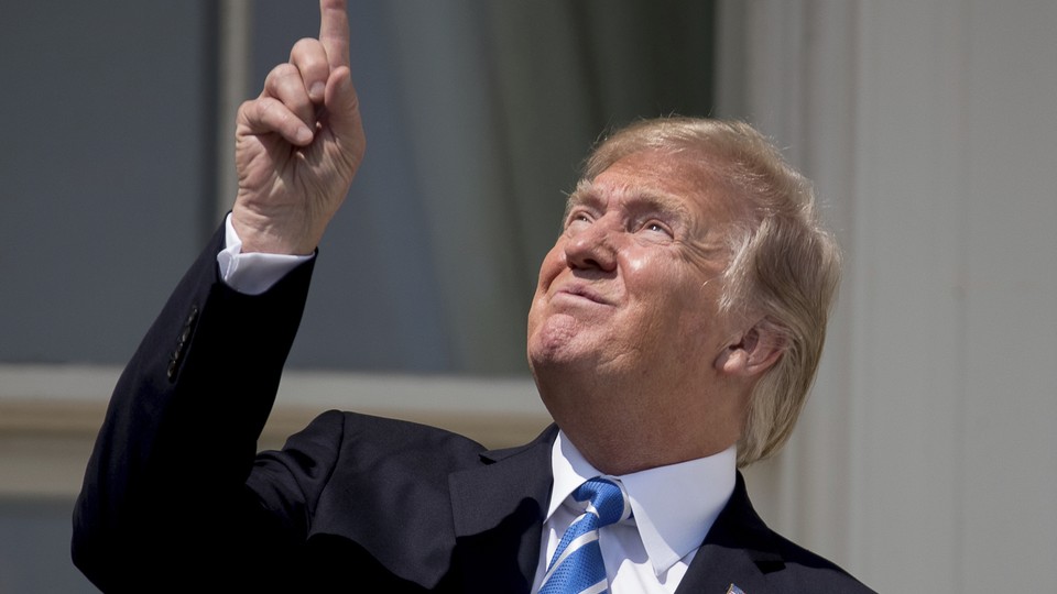 President Trump points at the sun as he views the solar eclipse at the White House.