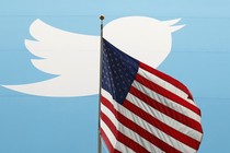 The Twitter logo behind a U.S. flag