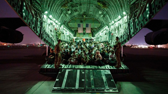 An aircrew assigned to the 816th Expeditionary Airlift Squadron assists evacuees aboard a C-17 Globemaster III aircraft in support of the Afghanistan evacuation.