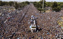 A huge crowd of fans jams up against a bus carrying Argentina's soccer team.