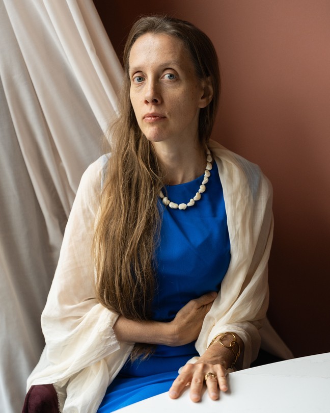 A woman in a blue dress sits at a white table