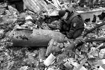 A man crouches next to unexploded ordnance in Ukraine.