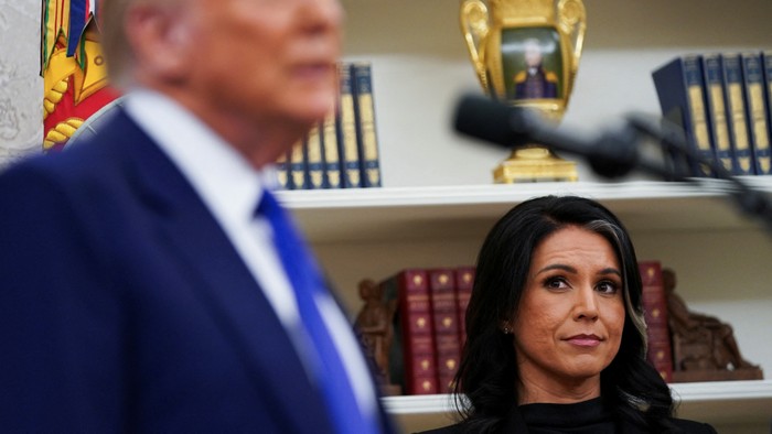 Tulsi Gabbard looks to the side at Donald Trump