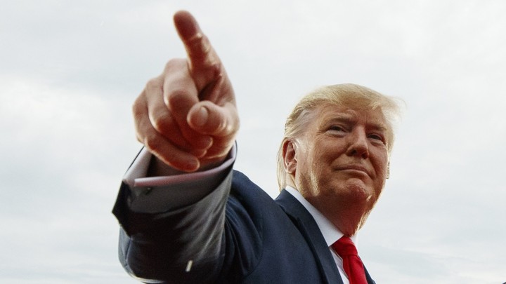 President Donald Trump points at a cheering crowd.