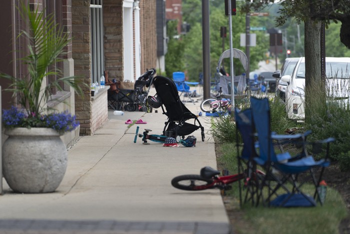 Abandoned lawn chairs and kids bikes stand at the scene of a Fourth of July parade shooting