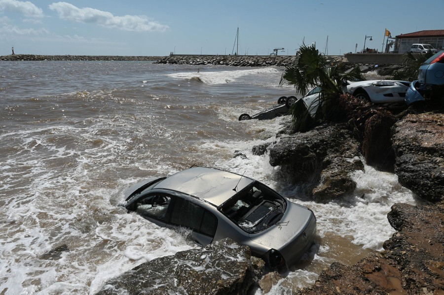 Waves crash against cars that were washed up to the seashore after a flood.
