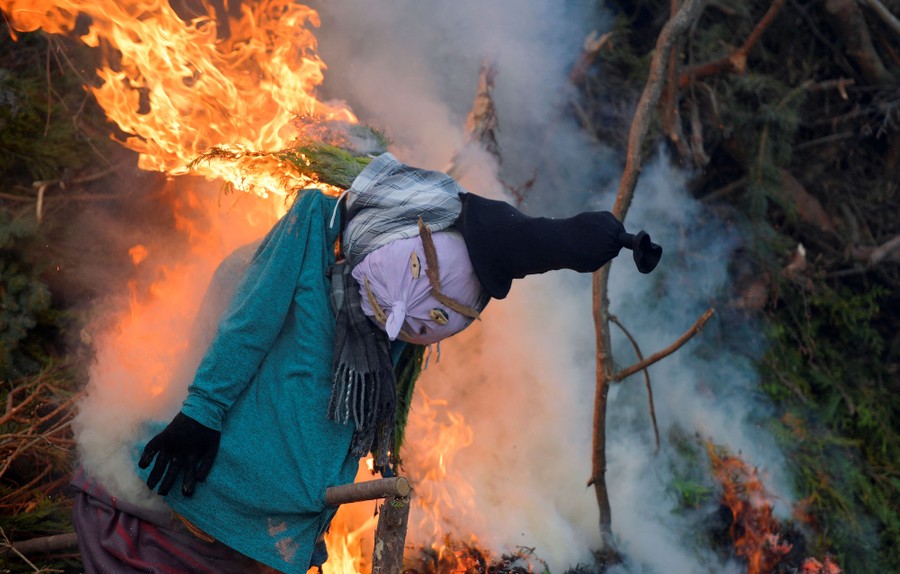 A puppet effigy burns on a pile of branches.
