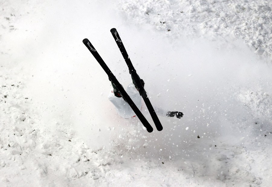 A skier is seen during a crash on a slope, snow flying up around them.