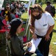 Two female political organizers speak to another woman on the sidelines of a soccer match.