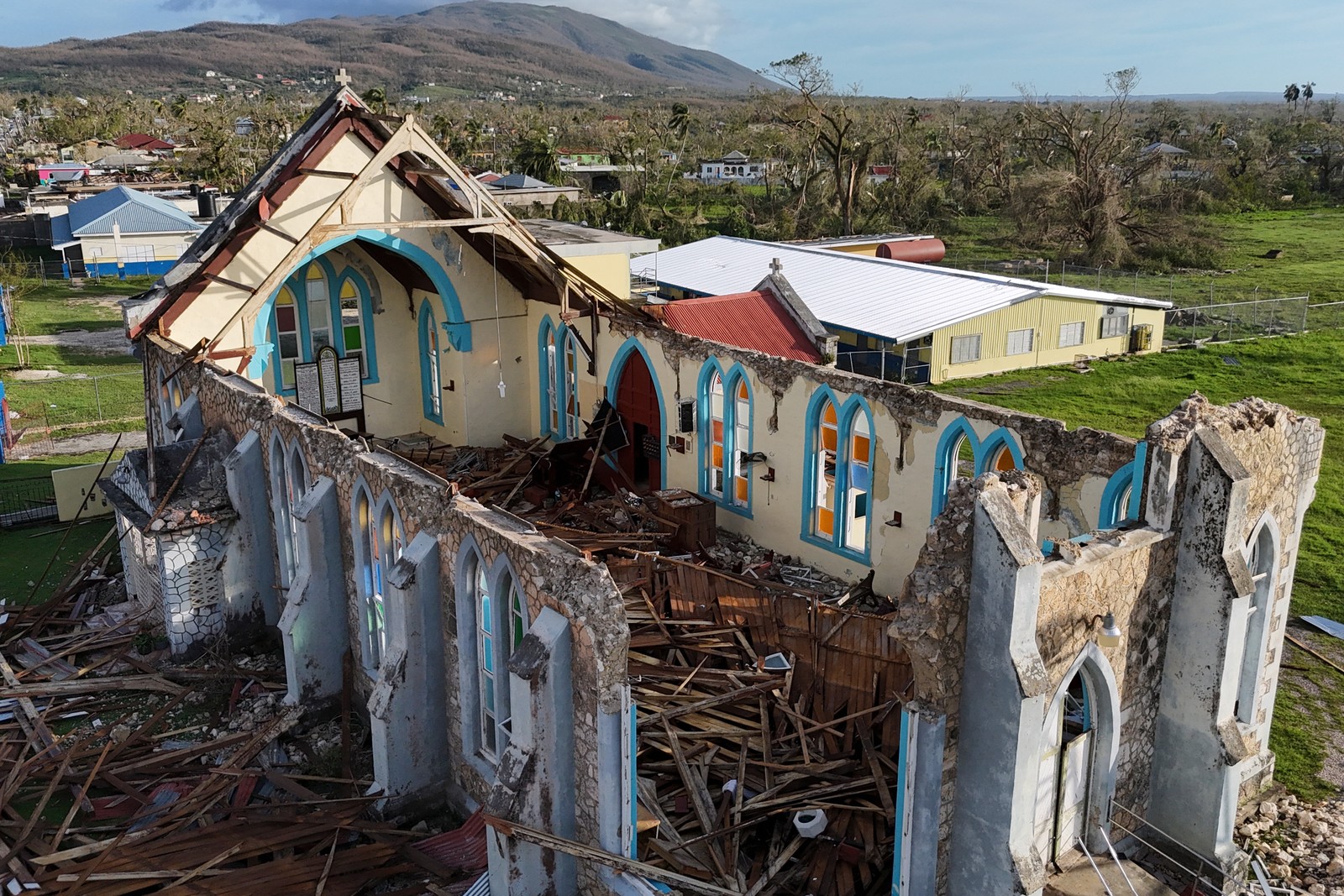 A badly storm-damaged church, its entire roof collapsed, seen among other storm debris.