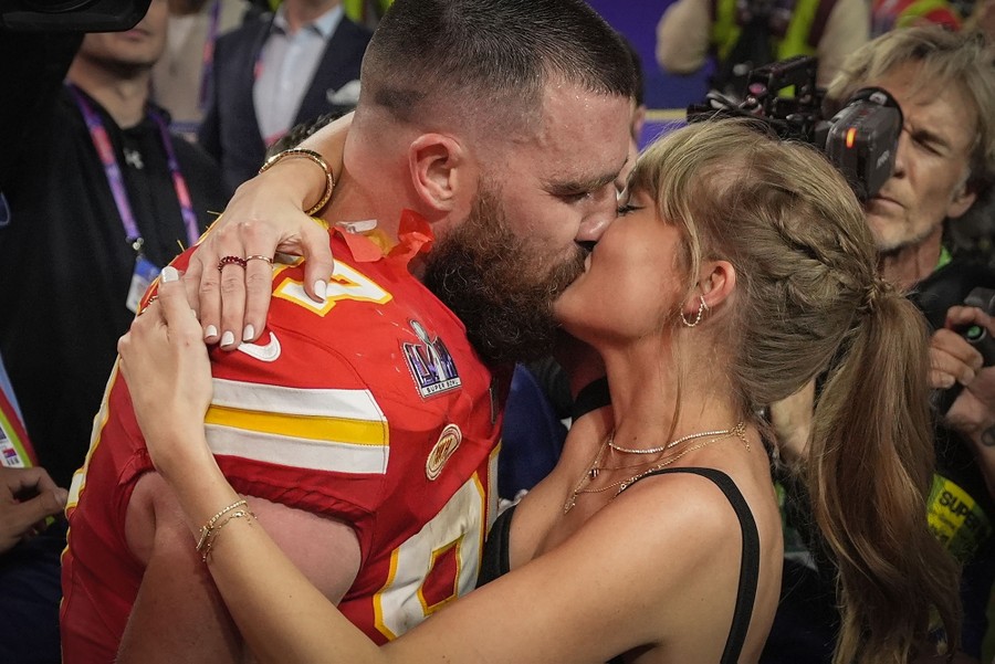 Kansas City Chiefs player Travis Kelce kisses Taylor Swift on the field after the Super Bowl.