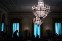 Trump speaks in a room with big chandeliers