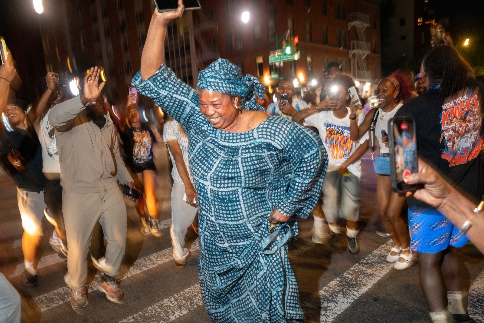 People dance and celebrate in a city street.