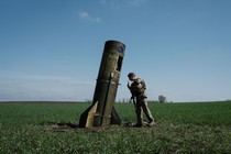 A soldier looks at the remains of part of a missile that dropped into a farm field.