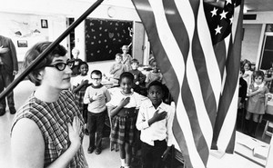 An archival photo of an American classroom saluting the American flag