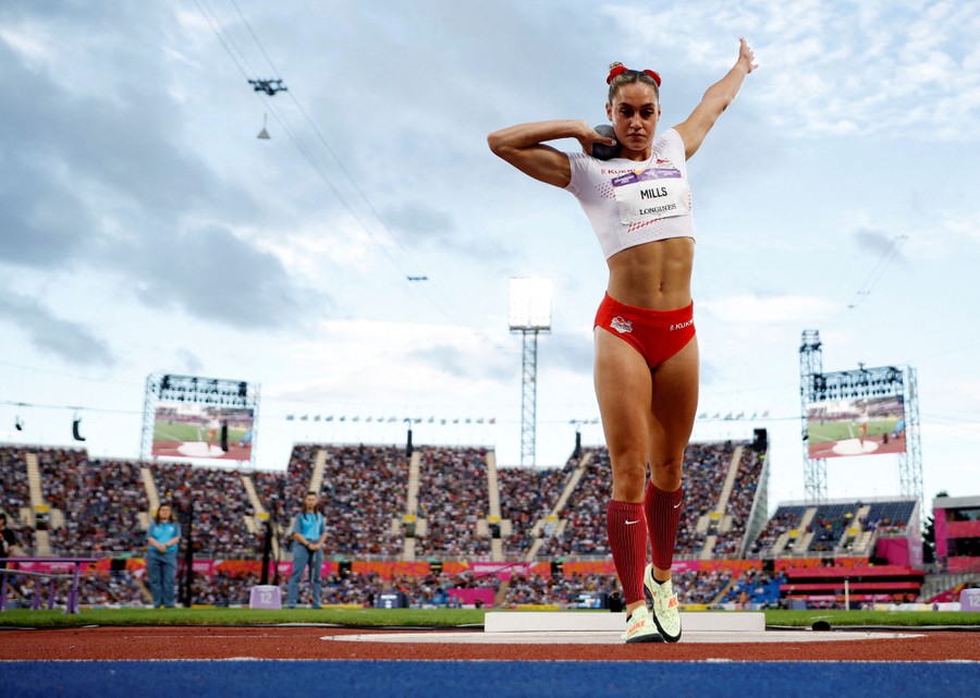 An athlete prepares to throw a shot put in a stadium.