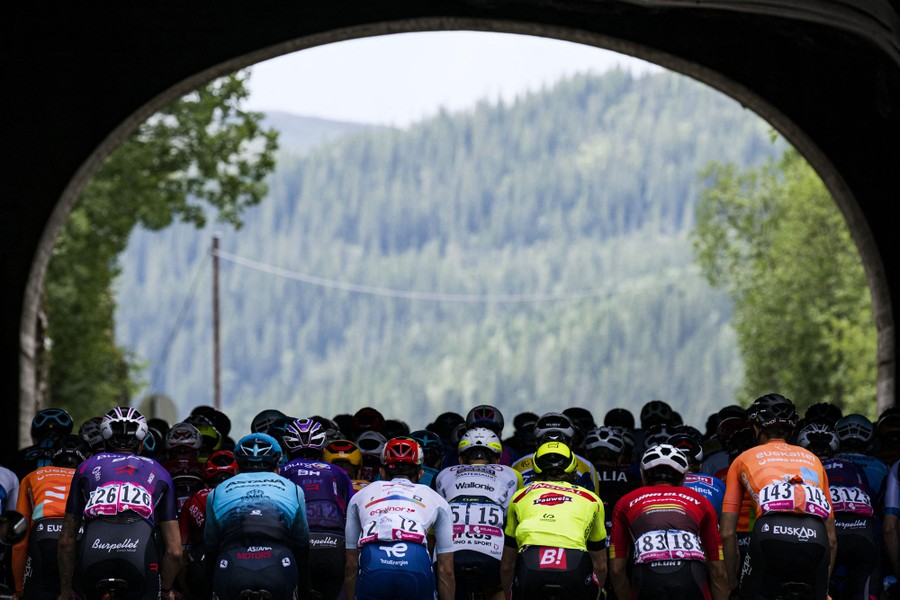 A pack of cyclists ride beneath an arch during a race.