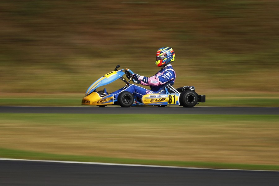 A Formula 1 race driver drives a small racing kart.