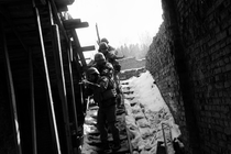 black-and-white photo of soldiers aiming weapons, descending open staircase in snow with sky behind