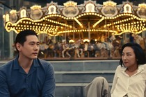 A man and a woman sitting in front of a carousel
