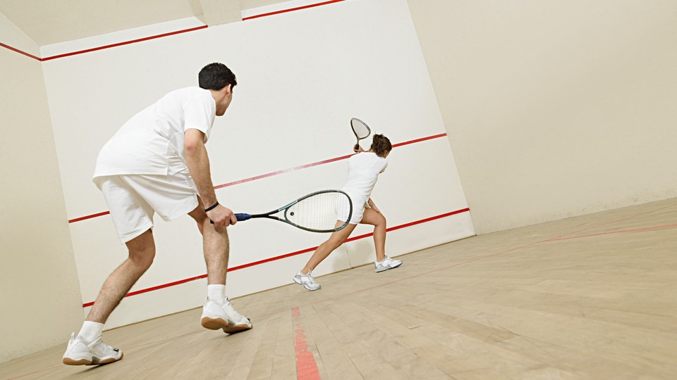 Two people wearing all-white playing squash together