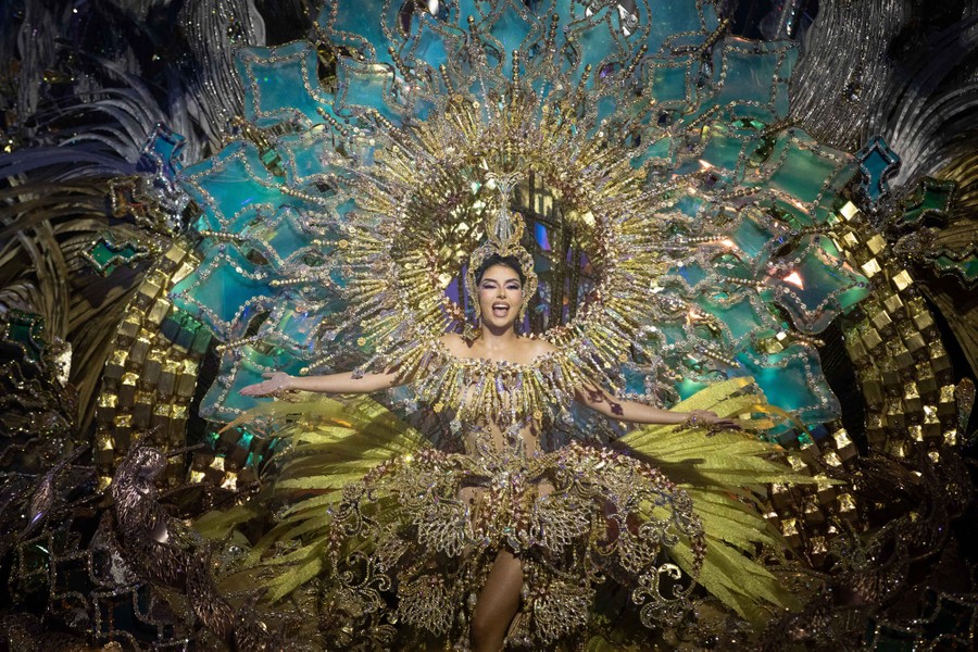 A person poses onstage, surrounded by an enormous decorative costume.