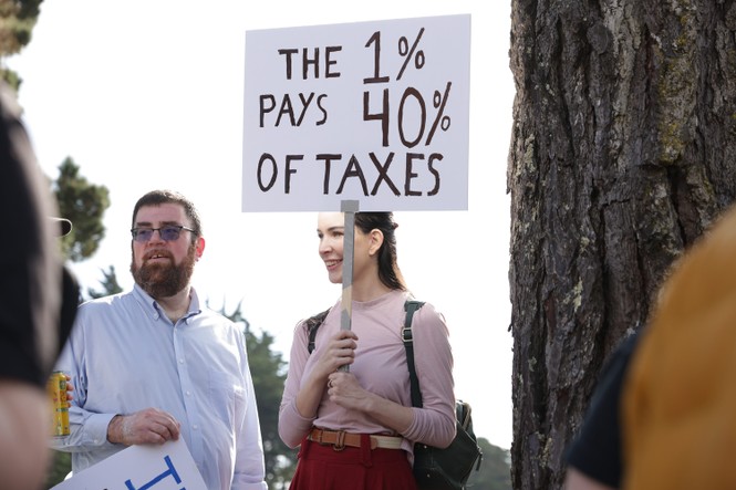 Image of person holding sign that says "The 1% Pays 40% of Taxes"