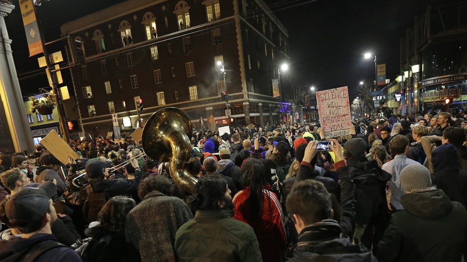 A crowd of protesters, including some with signs and one with a tuba, fill the streets in Berkeley, California, protesting a speech by Milo Yiannopoulos