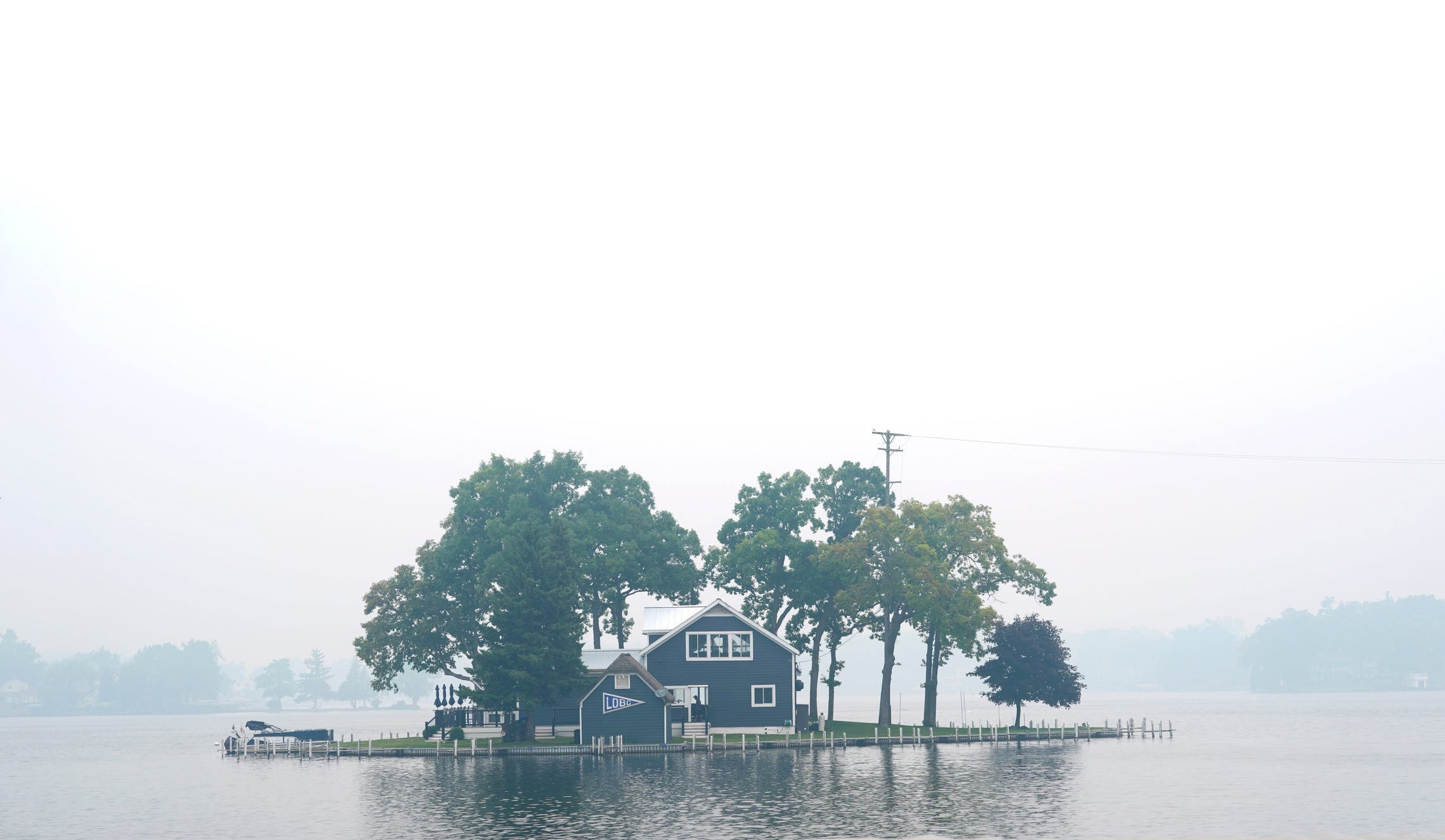 A boathouse on a small lake island, seen under a smoky sky