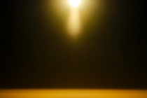 abstract photo of hazy moon-like light at top with golden halo on black background with golden horizon below