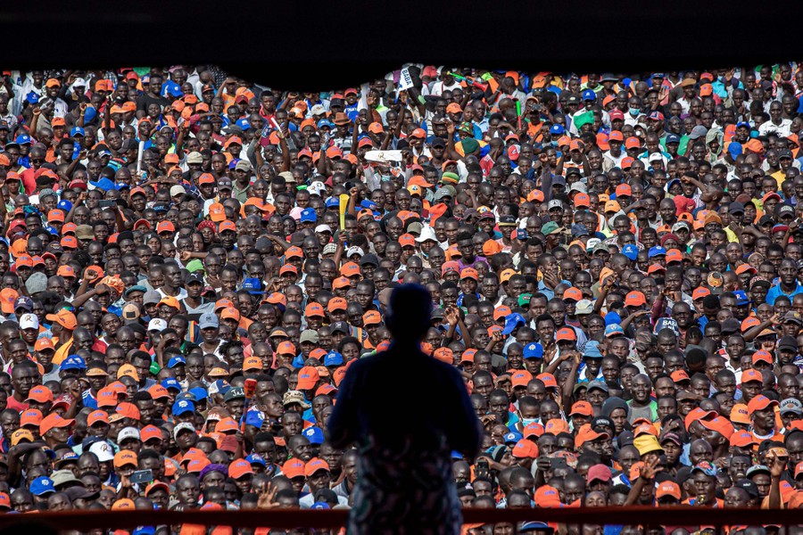 A person in silhouette, standing before a large crowd