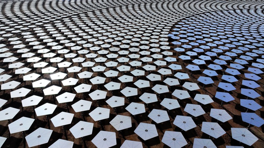 An aerial view of hundreds of pentagon-shaped mirrors arranged in a circular pattern