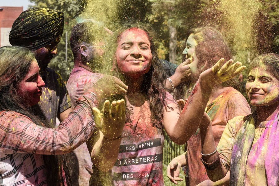 A half-dozen young people play and celebrate with colored powder.