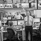 Black-and-white photo of Martin Baron standing in Washington Post newsroom near working reporters, desks, and screens