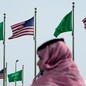 A man stands under American and Saudi flags