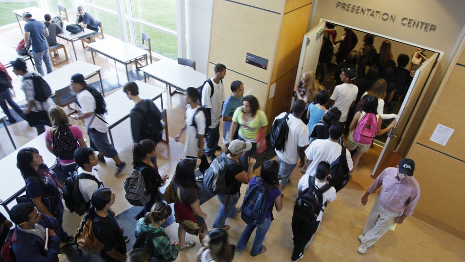 Students stand outside of a college lecture hall. 