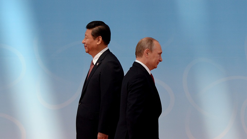 Xi Jinping and Vladimir Putin stand back to back in black suits, Xi towering over Putin.