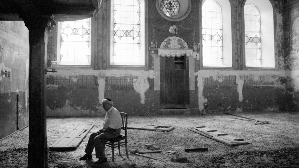 A man sits alone in a ruined synagogue in Russia.
