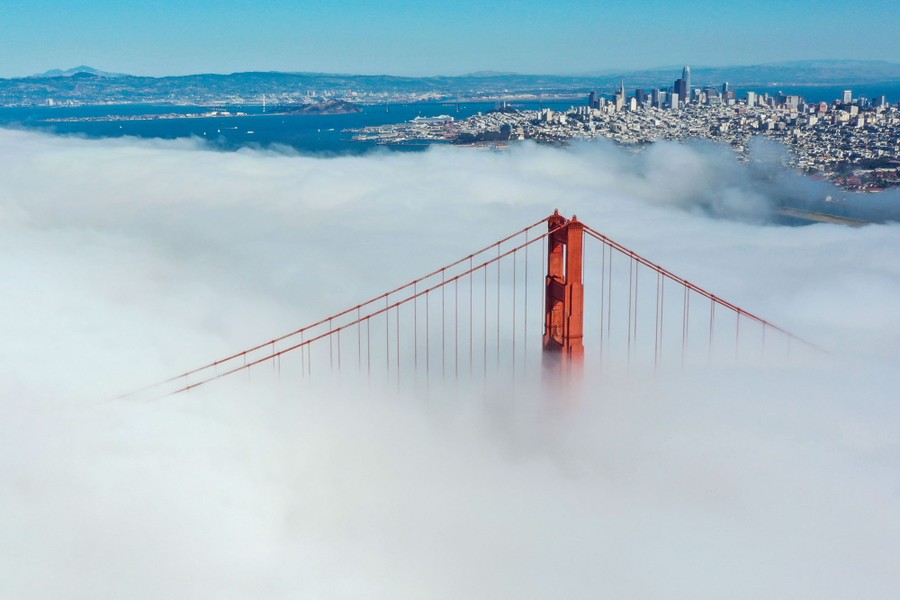 Fog blankets the Golden Gate Bridge, with the city of San Francisco in the background.
