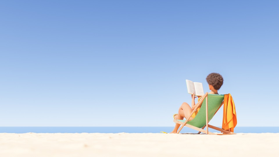 A woman sits on the beach reading a book