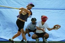 A player at bat strikes out while a Wiffle ball rests in the catcher's mitt.