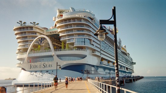 photo of Icon of the Seas, taken on a long railed path approaching the stern of the ship, with people walking along dock