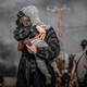 A mother covers her child's face to protect it from the smoke as Palestinians flee the northern part of Gaza to the central and southern parts, on November 10, 2023.