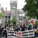 a large group of protestors are seen in front of a building holding signs that say 'Canada is still arming Israel'