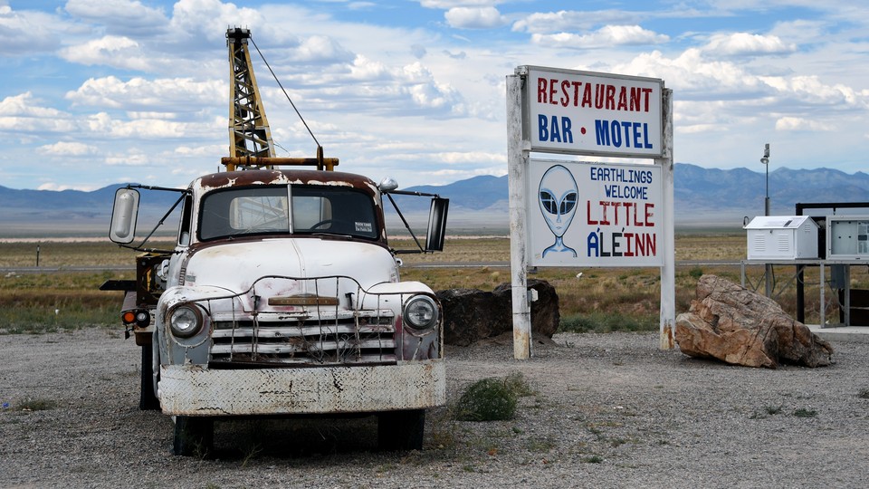 A tow truck parked beside a sign for the Little A'Le'Inn in Rachel, Nevada