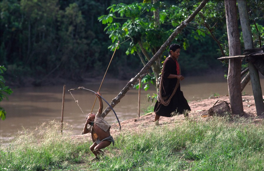 ASHANINKA INDIAN FISHING WITH BOW AND ARROW FROM A CANOE Stock