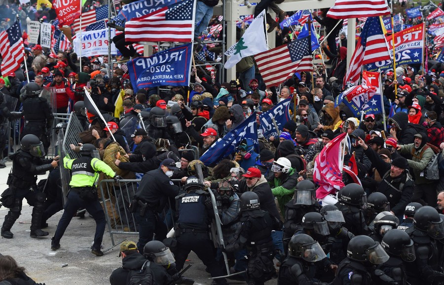 A large crowd of Trump supporters clash with a handful of police at a barrier.