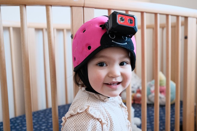 Luna at 18 months wearing a pink helmet with a camera attached to it