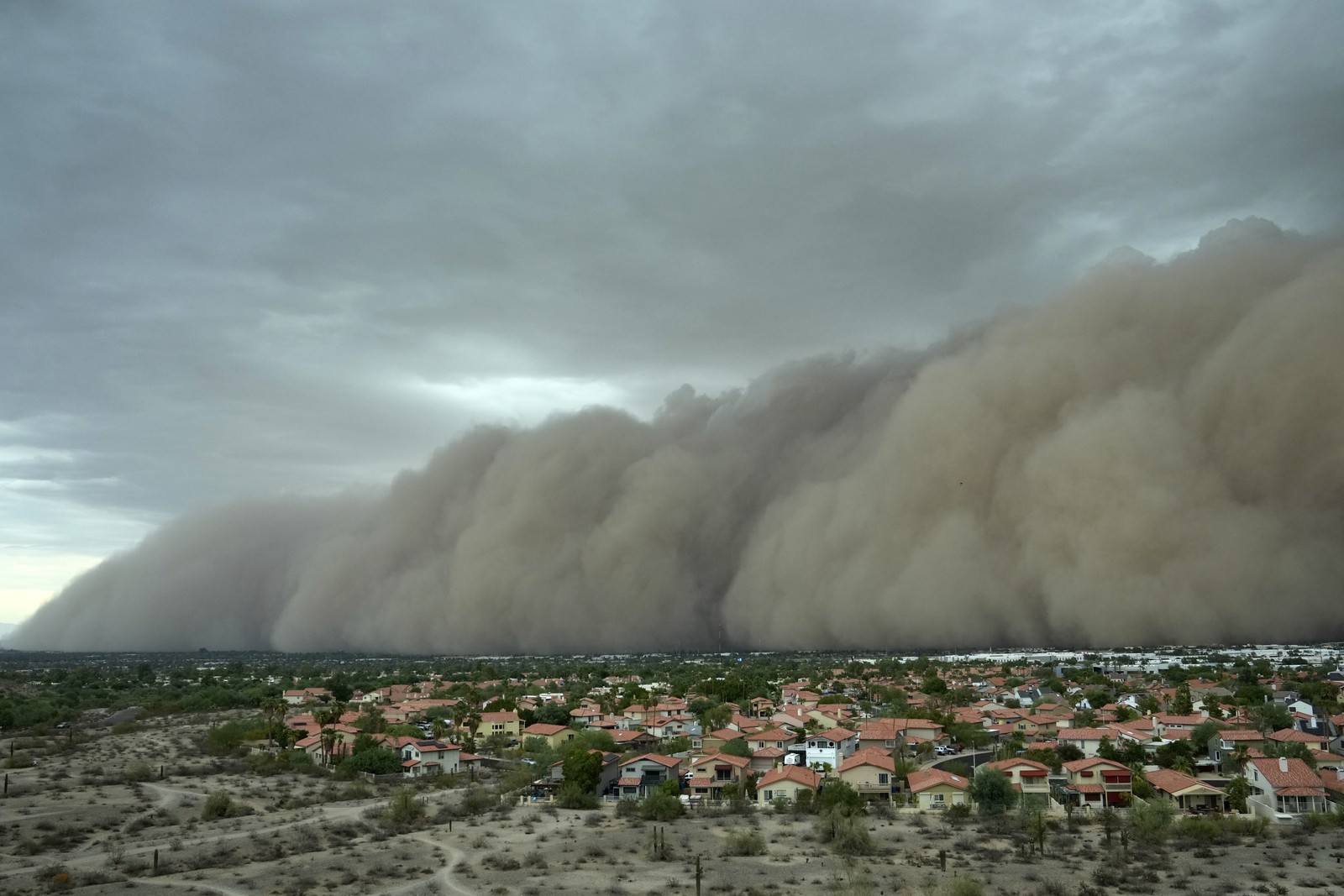 An enormous rolling cloud of dust approaches a residential area.