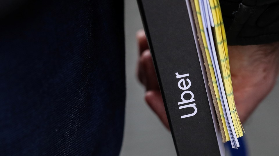 A close-up of a man carrying an Uber-branded binder